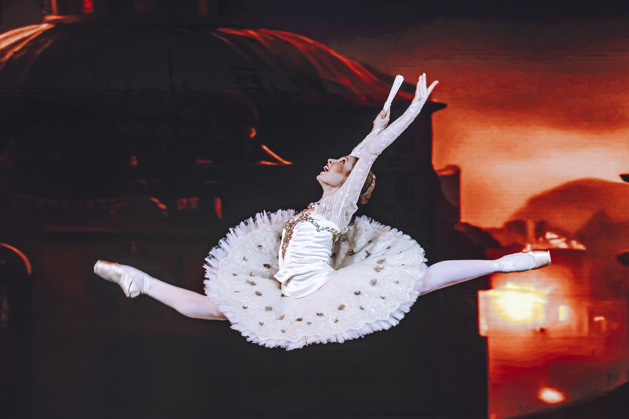Hannah Martin captured in a split leap on stage in a white classical tutu